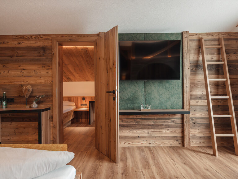 2-Raum-Familysuite mit viel hochwertigem Holz, Schreibtisch und Blick ins Kinderzimmer