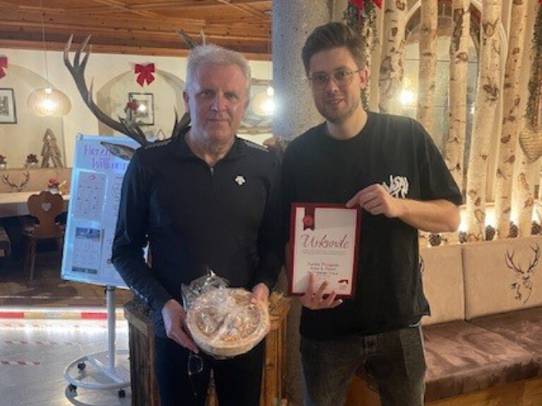 zwei Männer posieren anlässlich Gästeehrung mit Urkunde und Geschenk