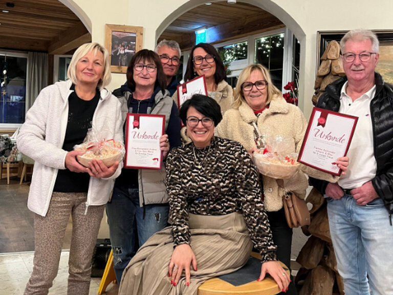 Mehrere Personen mit Gästeehrungsurkunde und die Gastgeberin lächeln in die Kamera