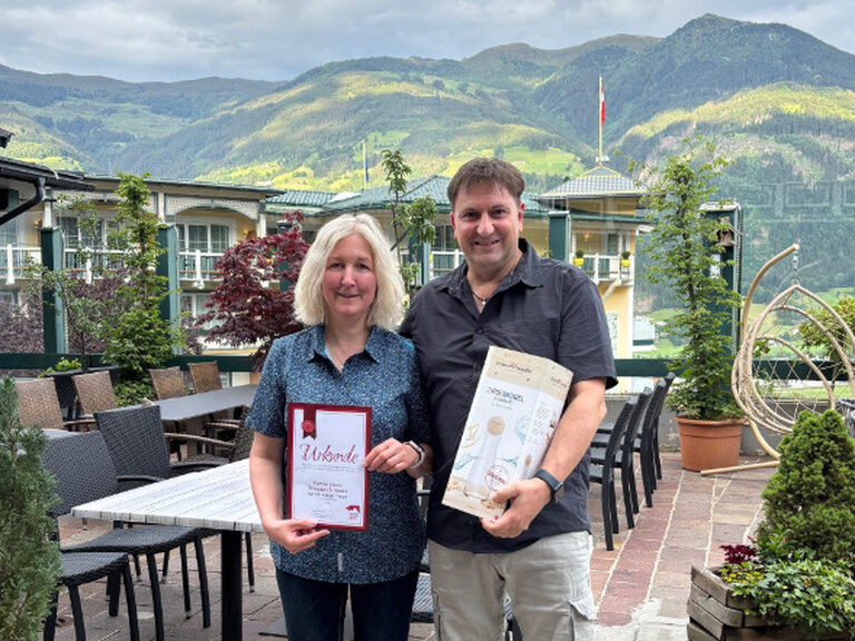 Paar posiert mit Ehrenurkunde auf der Gastterrasse des Kohlerhofs