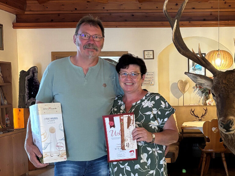 Paar posiert mit Ehrenurkunde und Geschenk vom Kohlerhof in der Lobby