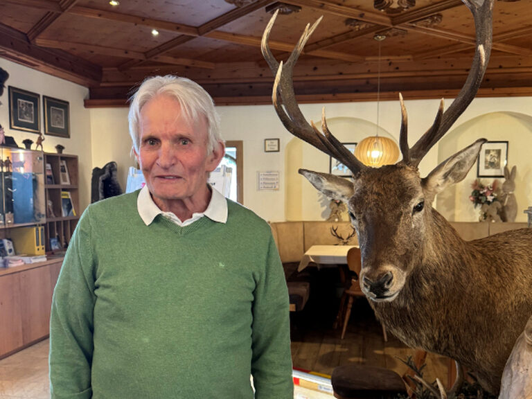 Mann mit grünem Pullover lächelt in die Kamera