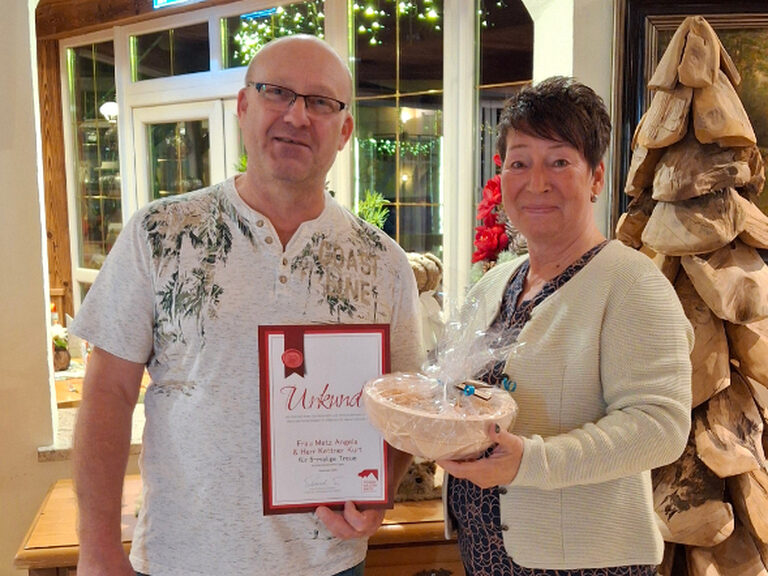 Paar posiert mit Urkunde anlässlich Gästeehrung