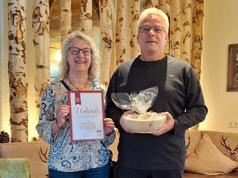 Paar posiert mit Ehrenurkunde und Geschenk vom Kohlerhof