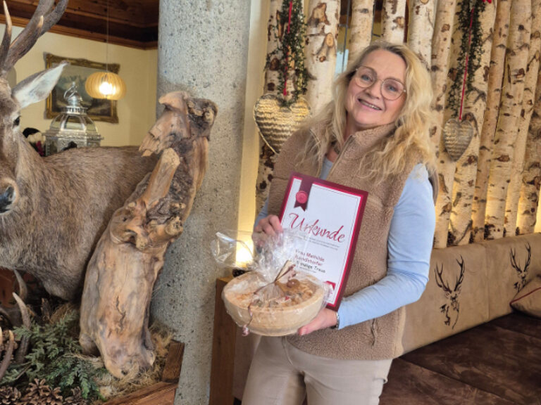 Frau posiert lächelnd mit Stammgasturkunde und Geschenk vom Hotel