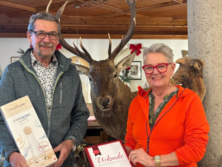 Paar posiert anlässlich Gästeehrung mit Urkunde und Geschenk