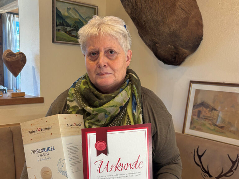 Frau posiert mit Treue-Urkunde und Geschenk vom Hotel Kohlerhof