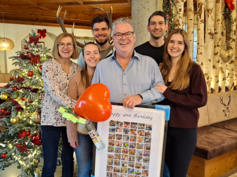 Familie lächelt glücklich in die Kamera und feiert einen runden Geburtstag eines Familienmitgliedes