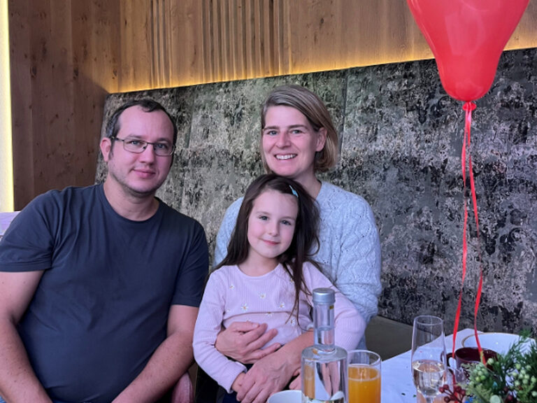 Familie sitzt lächelnd am dekorierten Geburtstagstisch