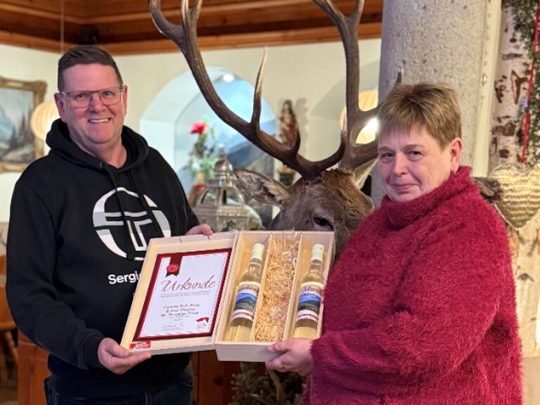 Paar hält Geschenk samt Urkunde anlässlich Gästeehrung in den Händen