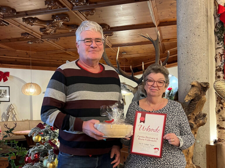 Paar posiert mit Urkunde und Geschenk anlässlich Gästeehrung