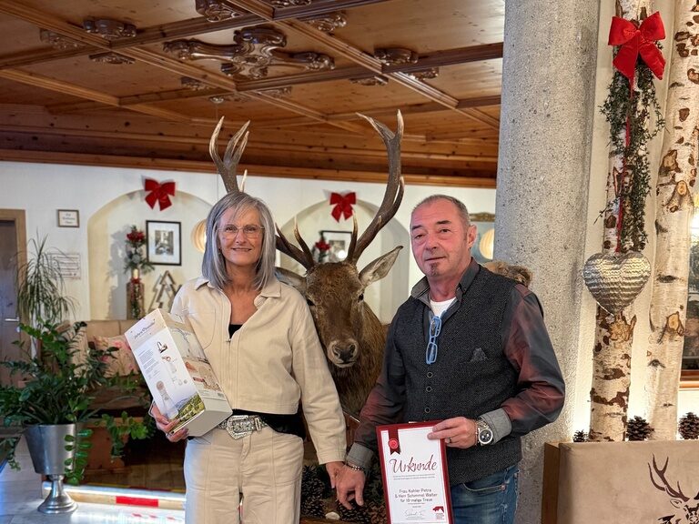 Paar posiert anlässlich Gästeehrung mit Urkunde