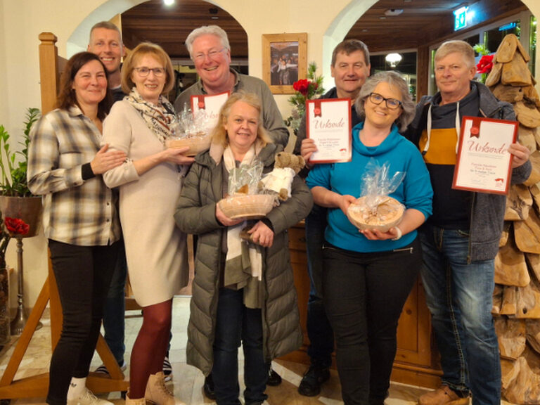 Mehrere Gäste stehen lächelnd, jeweils mit Urkunde und Geschenk vom Hotel anlässlich Gästeehrung, in der Hotellobby