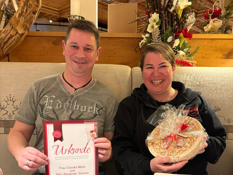 Paar posiert mit Urkunde anlässlich Gästeehrung