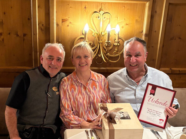 drei Personen posieren mit Urkunde anlässlich Gästeehrung