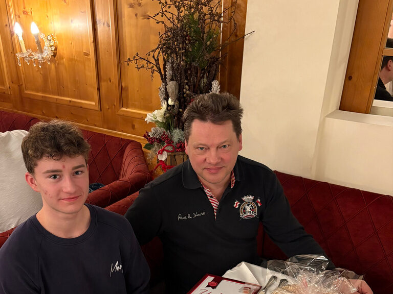 Mann und Junge sitzen am Tisch mit Urkunde und posieren anlässlich Gästeehrung