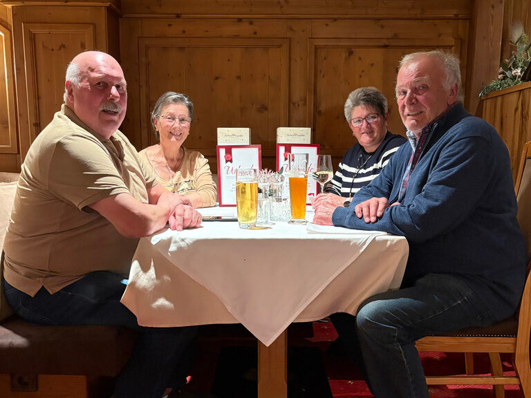 zwei Paare sitzen am Tisch mit Urkunde und posieren anlässlich Gästeehrung