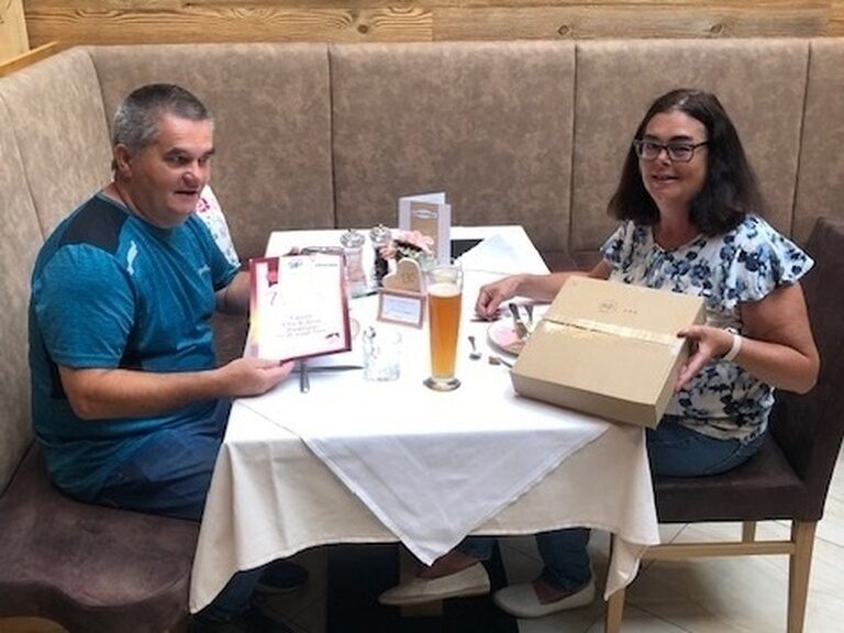 Paar sitzt am Tisch und posiert mit Urkunde anlässlich Gästeehrung