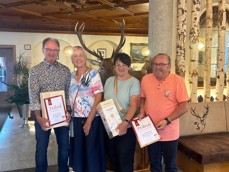 vier Personen posieren im Hotel mit Urkunde anlässlich Gästeehrung