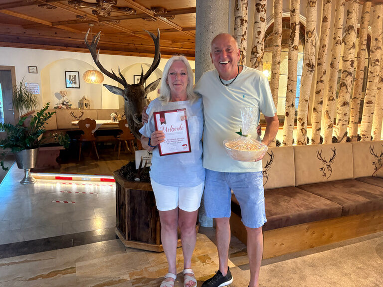 Paar posiert im Hotel mit Urkunde anlässlich Gästeehrung