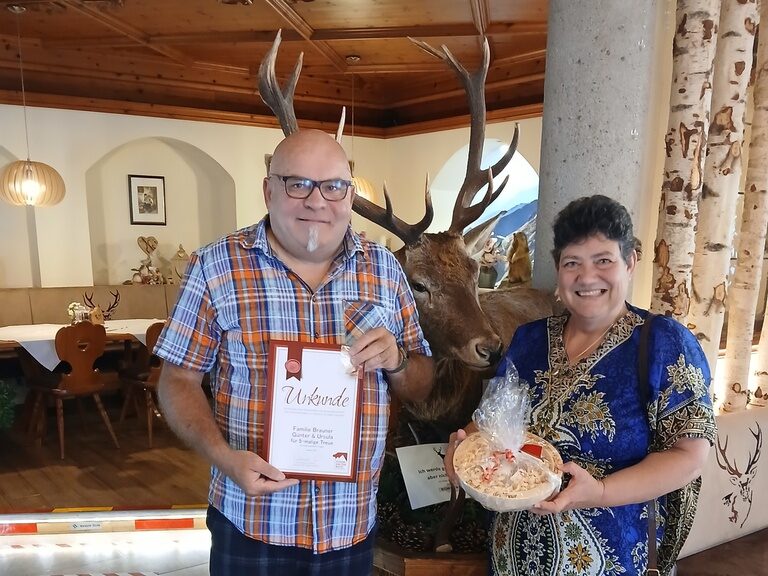 Paar posiert im Hotel mit Urkunde anlässlich Gästeehrung