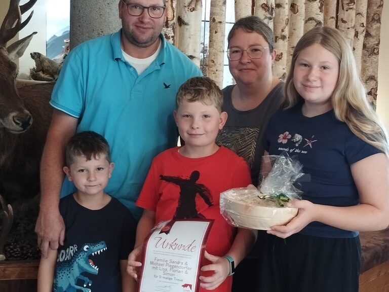 Familie posiert im Hotel mit Urkunde anlässlich Gästeehrung