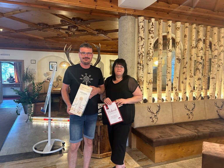 Paar posiert im Hotel mit Urkunde anlässlich Gästeehrung