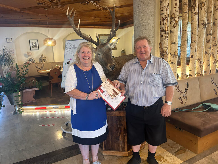 Paar posiert im Hotel mit Urkunde anlässlich Gästeehrung