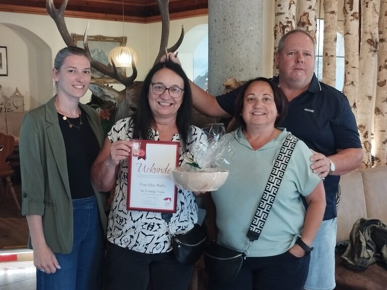 Familie posiert im Hotel mit Urkunde anlässlich Gästeehrung