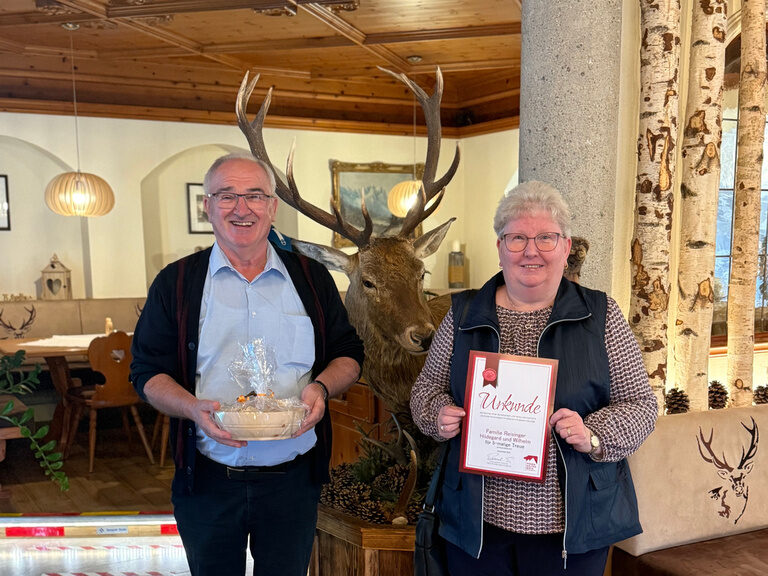Paar posiert mit einer Urkunde anlässlich Gästeehrung