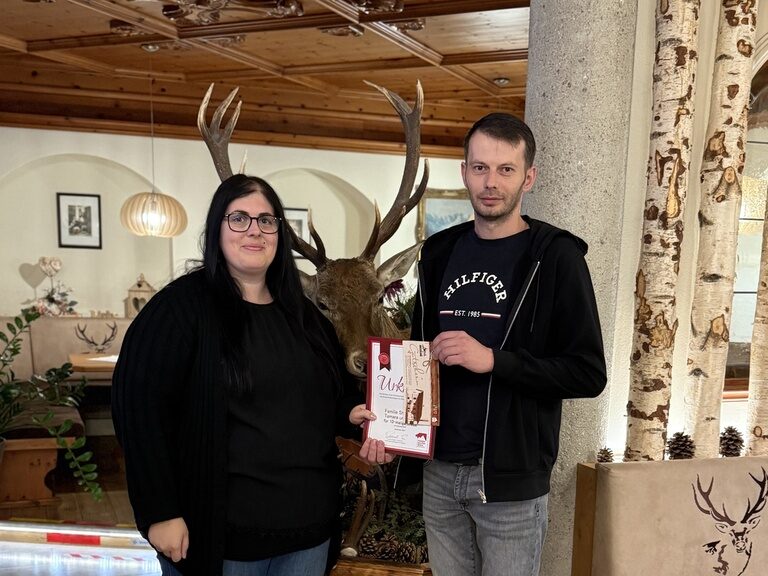 Paar posiert mit einer Urkunde anlässlich Gästeehrung