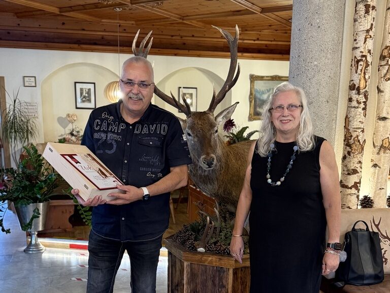 Paar posiert mit einer Urkunde anlässlich Gästeehrung