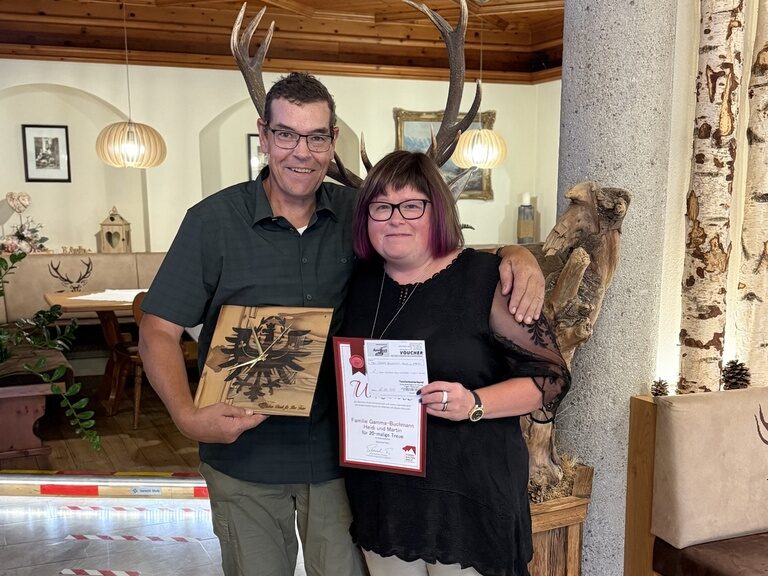 Paar posiert mit einer Urkunde anlässlich Gästeehrung