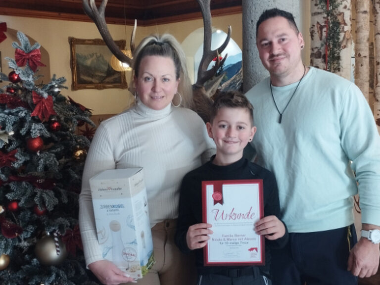 Familie posiert mit Urkunde anlässlich Gästeehrung, im Hintergrund ist weihnachtliche Deko zu sehen
