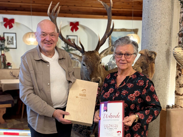 Paar posiert anlässlich Gästeehrung mit Urkunde und Geschenk