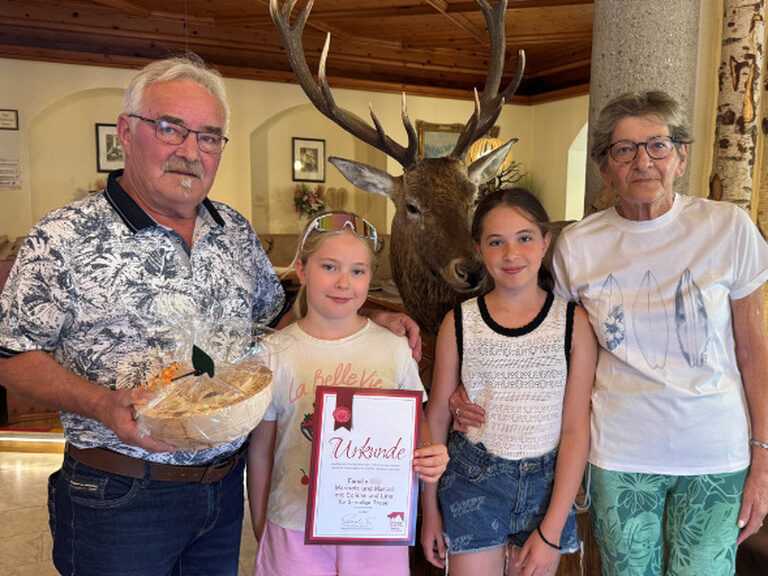 Familie posiert mit Ehrenurkunde und Geschenk vom Hotel
