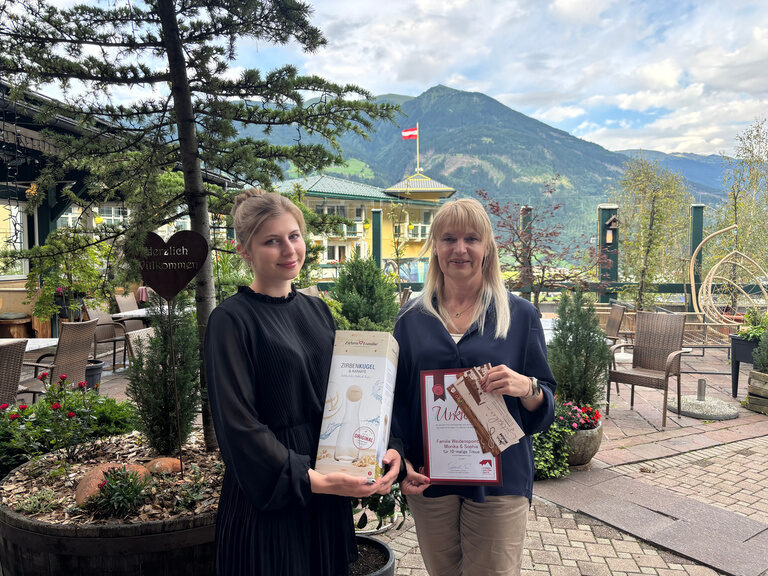 zwei Frauen posieren im Gastgarten mit Urkunde anlässlich Gästeehrung