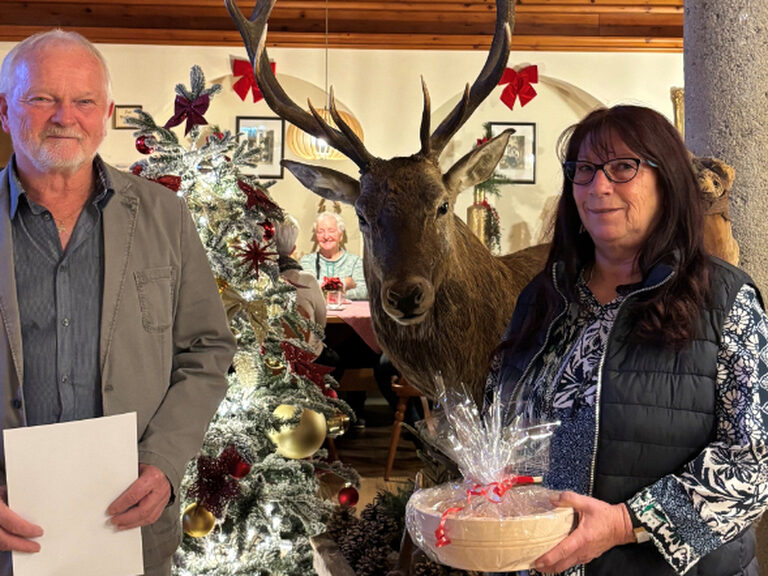 Paar posiert anlässlich Gästeehrung mit Urkunde und Geschenk