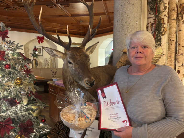 Frau posiert mit Gästeehrungsurkunde