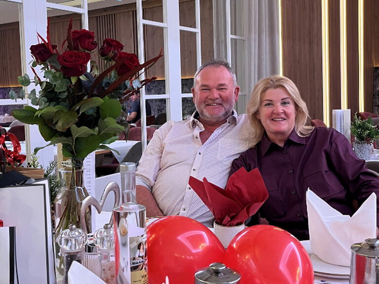 Paar sitzt lächelnd am dekorierten Geburtstagstisch