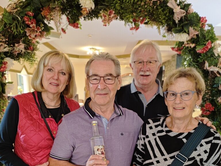 4 Personen posieren unter einem Blumenbogen anlässlich Geburtstag