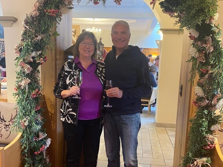 Paar posiert anlässlich Geburtstag unter einem Blumenbogen