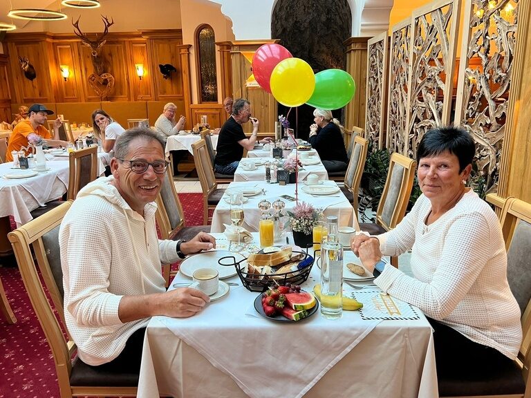 Paar sitzt am dekorierten Frühstückstisch und posiert anlässlich Geburtstag