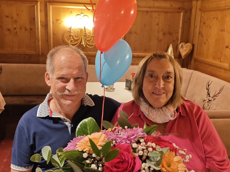 Paar posiert mit buntem Blumenstrauß und Luftballonen anlässlich Geburtstag