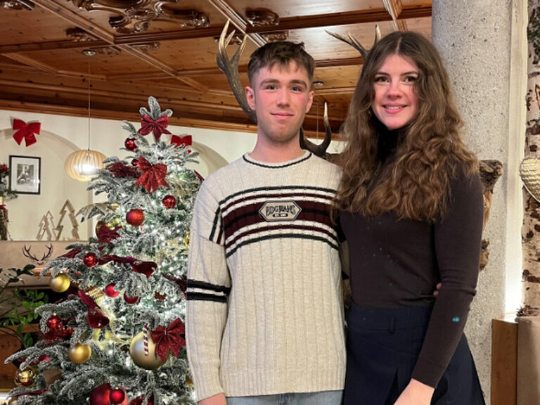 Paar posiert anlässlich Geburtstag, im Hintergrund ist der festlich geschmückte Weihnachtsbaum zu sehen