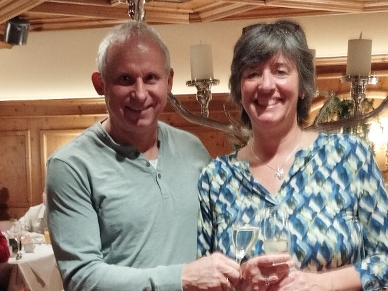 Paar lächelt anlässlich eines Geburtstags mit jeweils einem Glas Sekt in der Hand in die Kamera