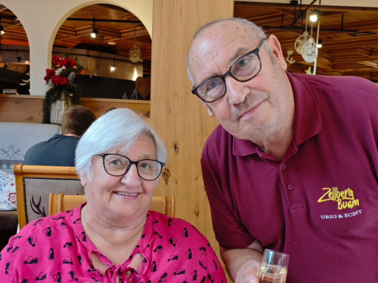 Aufgrund des Geburtstages der Frau posiert ein Paar mit je einem Glas Sekt