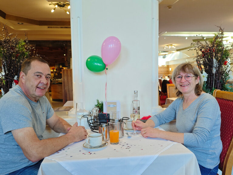 Paar sitzt lächelnd am dekorierten Geburtstagstisch