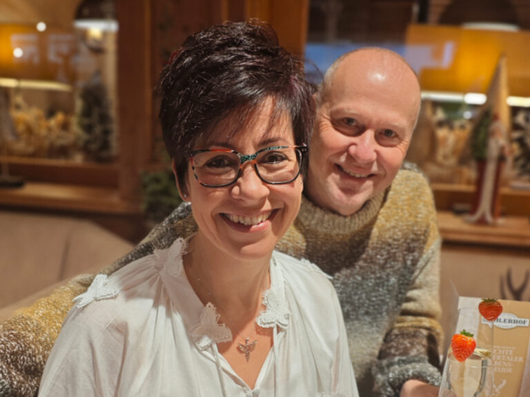 Paar lächelt anlässlich des Geburtstags der Frau in die Kamera