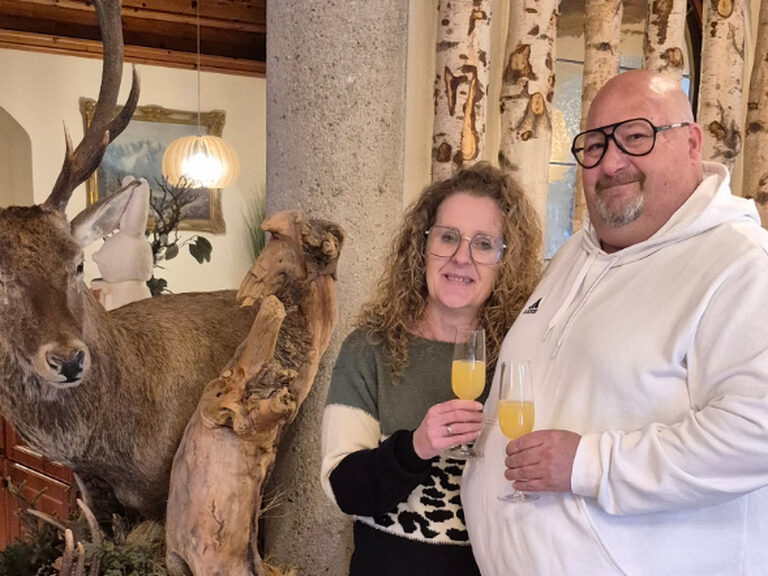Paar posiert mit einem Glas Orangensaft und stößt auf den Geburtstag an